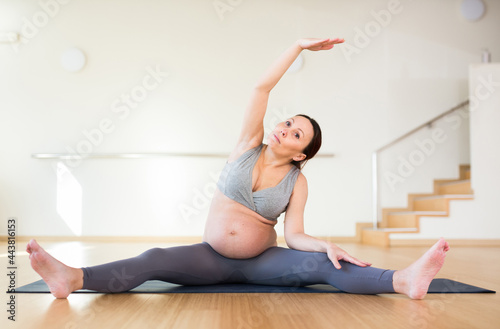 Pregnant woman is engaged in yoga. Revolved seated side angle pose or Parivrtta Upavistha Konasana
