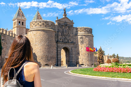 Woman with her back facing the Puerta de la Bisagra (Gate of Bisagra) in the medieval city of Toledo, Spain.