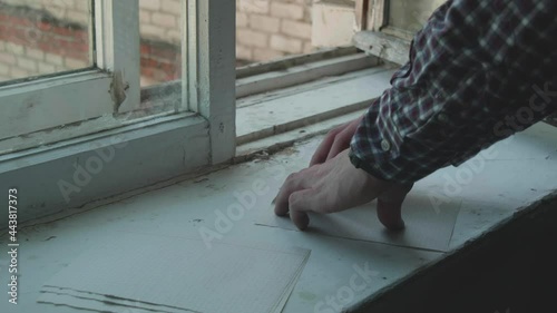 A man makes a paper airplane on a windowsill. Retro vintage window. High School Years.