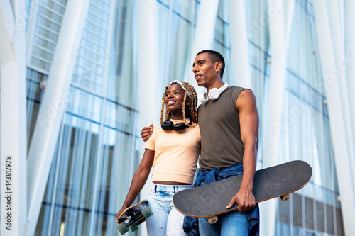  Beautiful couple having fun outdoors. Portrait of an excited young couple with skateboard.