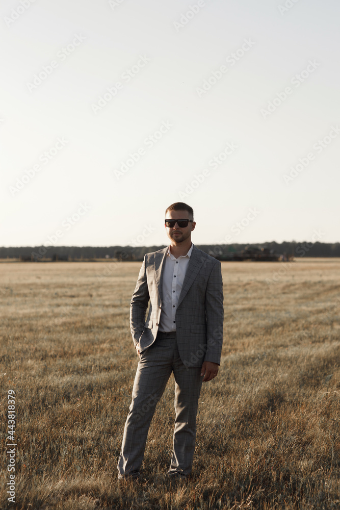 The groom in a suit is standing near his private plane. A male pilot, against the background of an airplane at sunset.