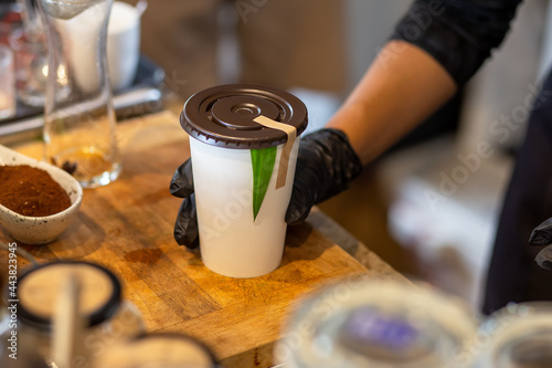 selective focus. dark brown lid decorated White paper coffee cup fragrant green pandan leaves. The green color makes it look like a refreshing natural drink. white portion for text