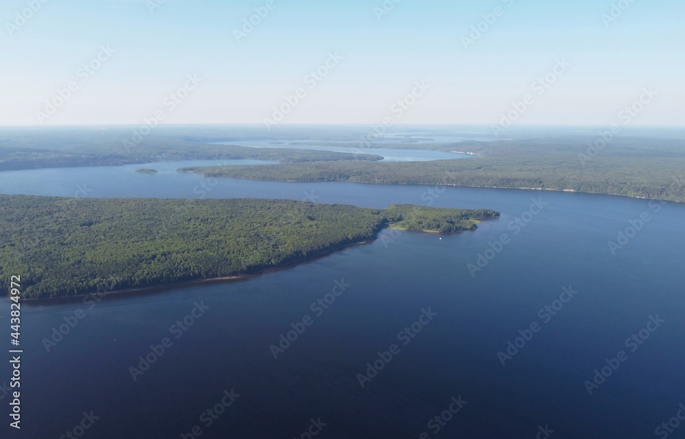 A wide river winds and goes into the distance against the background of the forest. Photo from the drone
