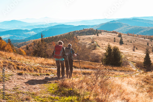 Two active senior people are hiking at the autumn morning mountains