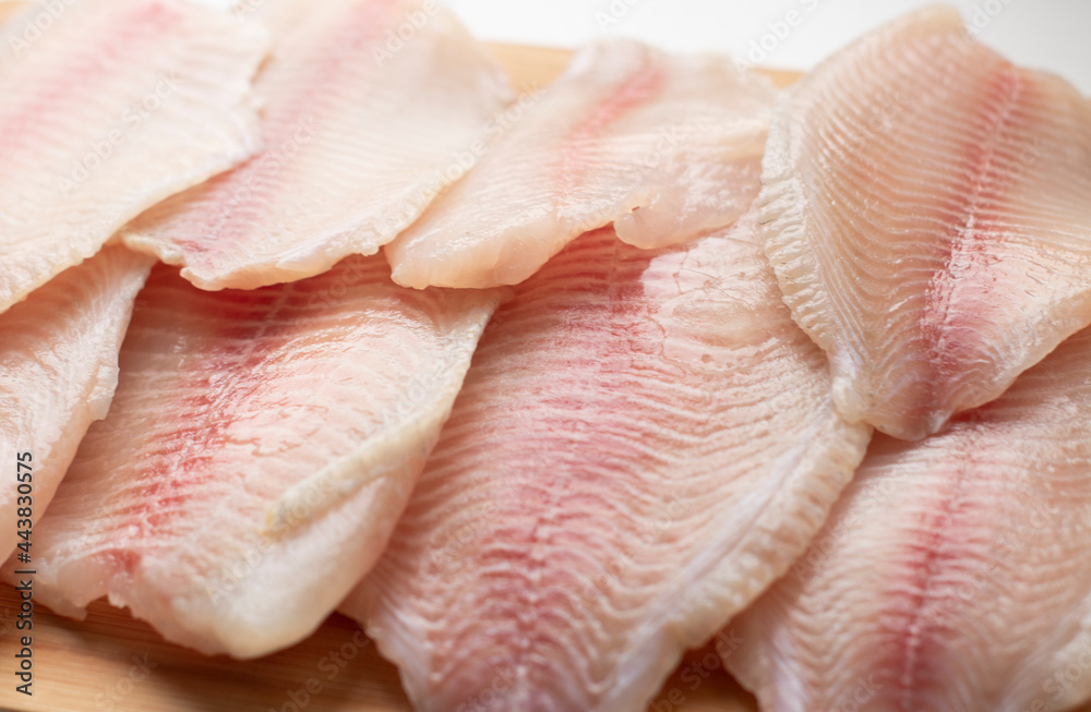 pieces of raw fish, tilapia on a wooden surface. Fresh fish, seafood, vitamins, d3. The benefits or harms of seafood, deficiency pieces of raw fish, tilapia on a wooden surface. Fresh fish, seafood, vitamins, d3. The benefits or harms of seafood, deficiency
