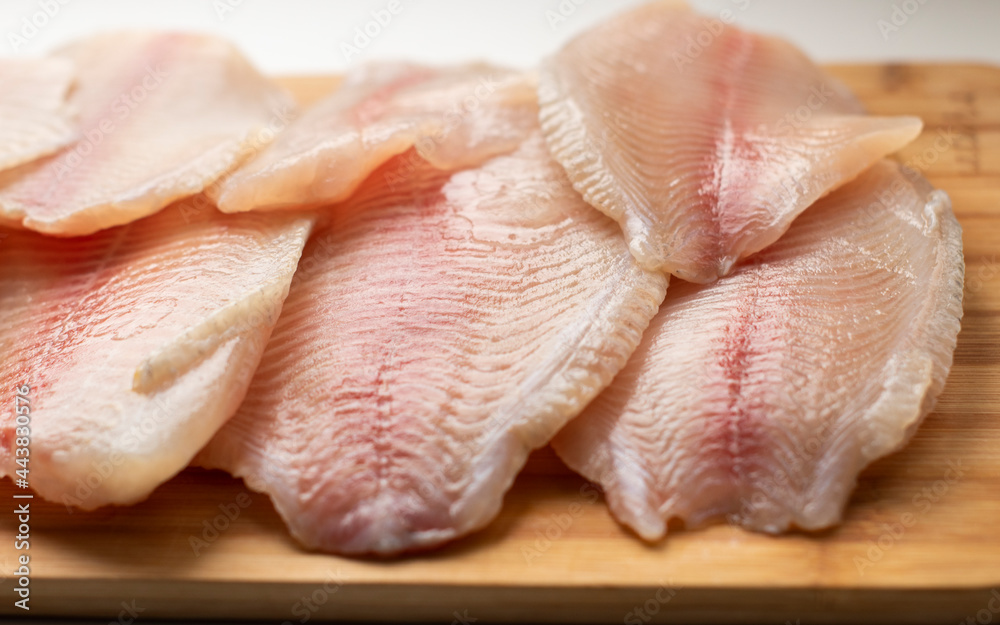 pieces of raw fish, tilapia on a wooden surface. Fresh fish, seafood, vitamins, d3. The benefits or harms of seafood, deficiency pieces of raw fish, tilapia on a wooden surface. Fresh fish, seafood, vitamins, d3. The benefits or harms of seafood, deficiency