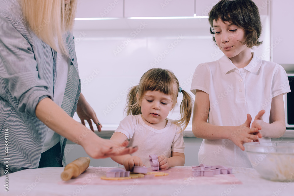 Mom with two daughters makes dough figurines using cookie cutters. Mom with two daughters makes dough figurines using cookie cutters.