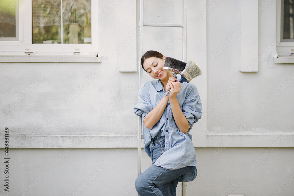 Cute girl standing near wall with repair tools Cute girl standing near wall with repair tools