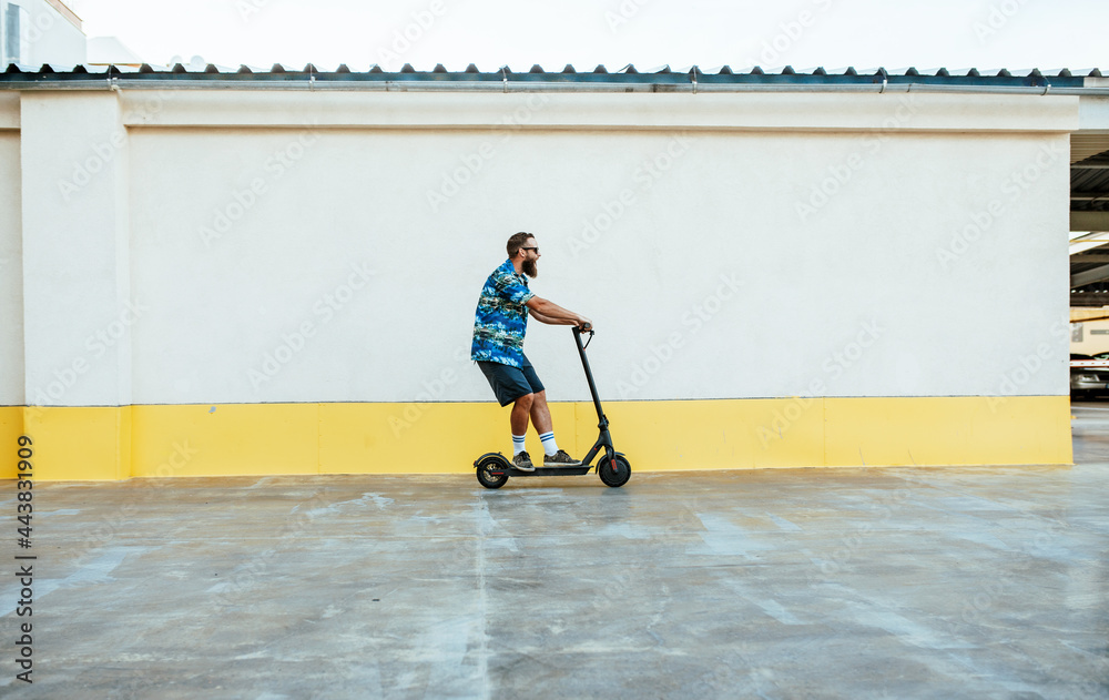 Obraz premium Young hipster man driving electric scooter in bright sunny day. Ecological transportation concept.
