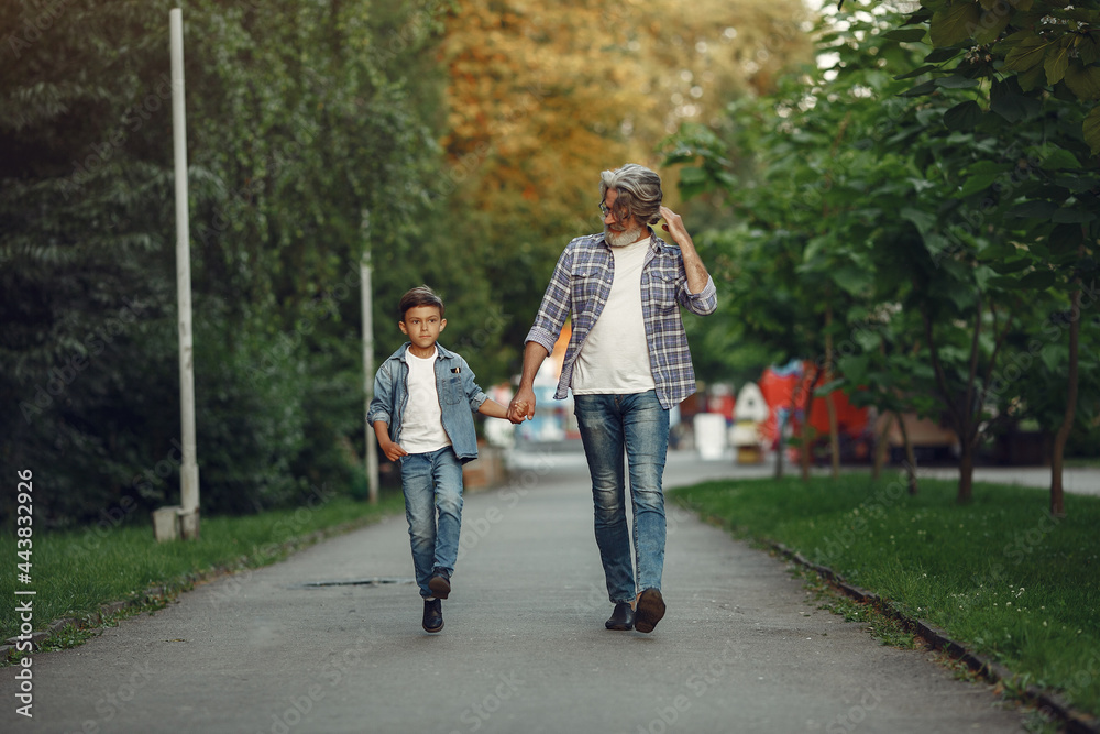 Grandfather with grandchild walking in a summer park Grandfather with grandchild walking in a summer park