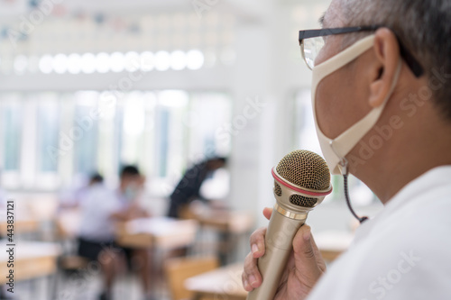 Speaker Professor female Asian teaching explain wear Medical face mask for safety speaking microphone at whiteboard in classroom in university. Teacher in Health care prevent COVID-19 disease epidemic