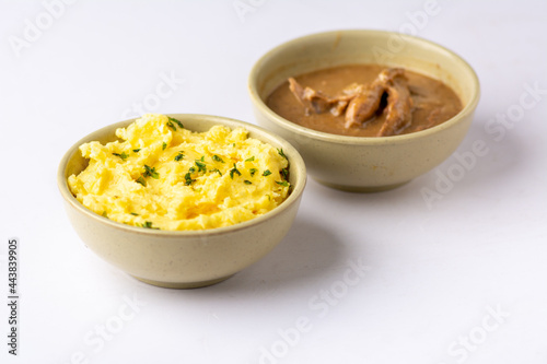 Mashed potatoes with herbs served with chicken sauce on a white background
