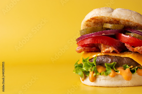 Beef burger with cheese and bacon on yellow background. Copy space