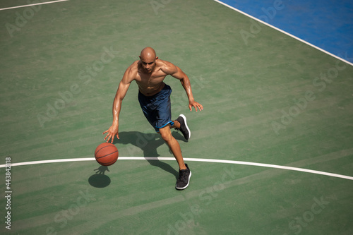 Top view of young man, male basketball player playing basketball at street public stadium, sport court or palyground outdoors. Summer sport games. © master1305