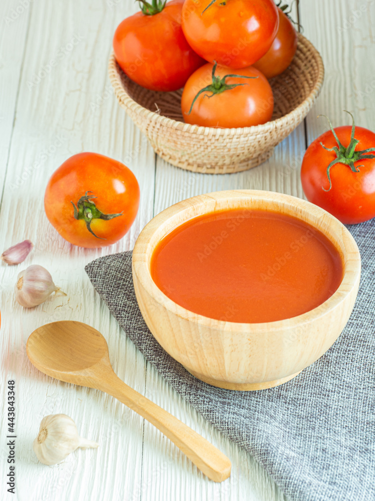 Delicious tomato soup in wooden bowl and tomatos on white wood table, Copy space for word. Healthy food in morning concept. Verticle picture. Delicious tomato soup in wooden bowl and tomatos on white wood table, Copy space for word. Healthy food in morning concept. Verticle picture.