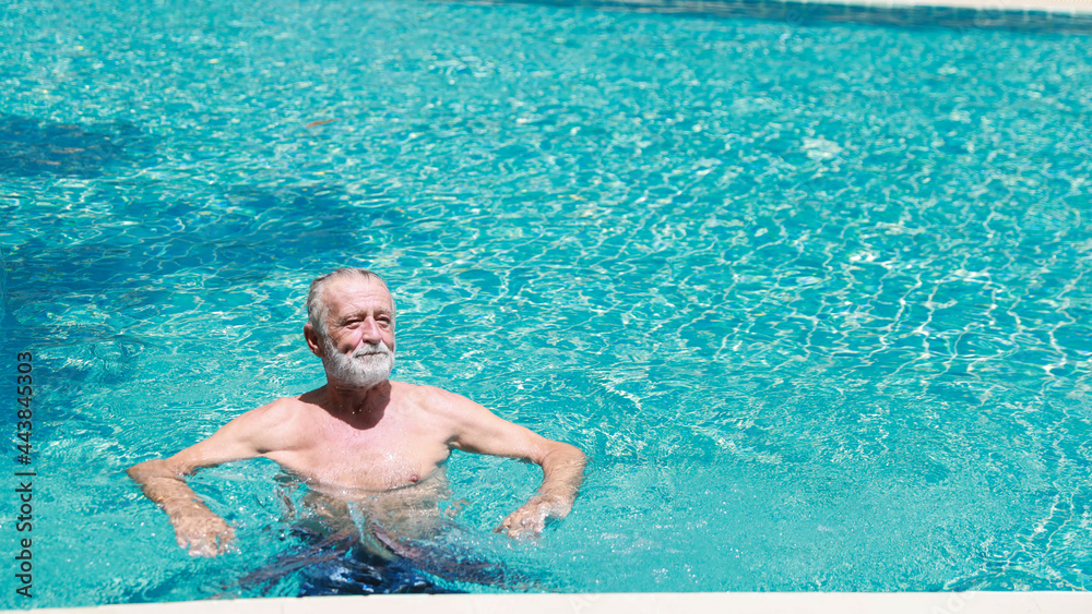 happy elderly caucasian swimming in pool during retirement holiday with relaxation and smiling