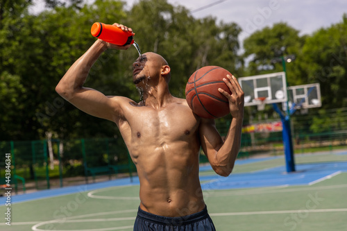 Young strong man, male basketball player training at street public stadium, sport court or palyground outdoors. Concept of healthy active lifestyle, motion, hobby. photo