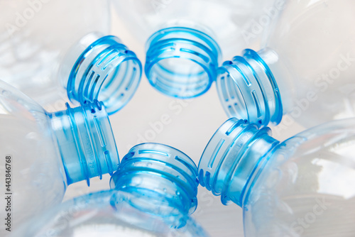 Transparent plastic bottles, on a clear surface. Transparent bottle neck. Recycling and disposal of single-use plastics. 
