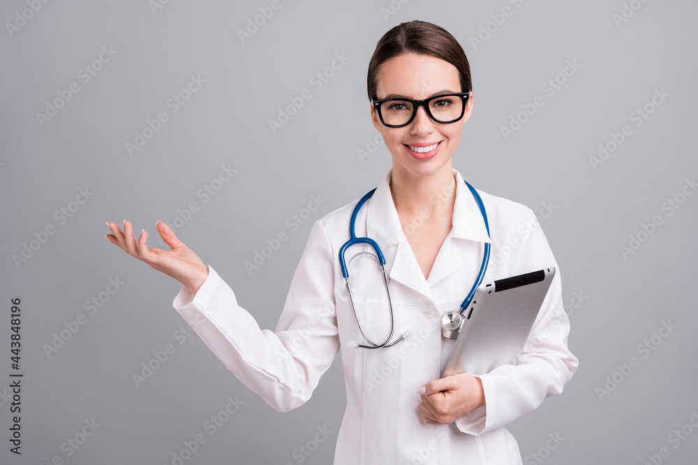 Photo portrait young nurse with sthethoscope smiling keeping tablet showing copyspace isolated grey color background Photo portrait young nurse with sthethoscope smiling keeping tablet showing copyspace isolated grey color background