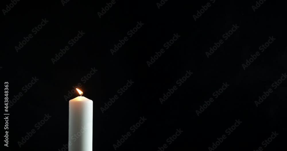 White burning candle in the night. A view of a white candle for hope ritual on the black background. White burning candle in the night. A view of a white candle for hope ritual on the black background.