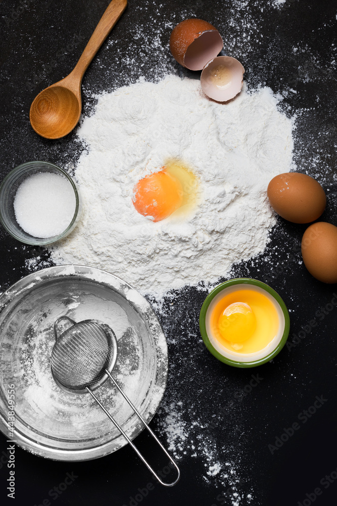 Ingredients for baking - flour sugar and eggs on dark background - Top view with copy space Ingredients for baking - flour sugar and eggs on dark background - Top view with copy space