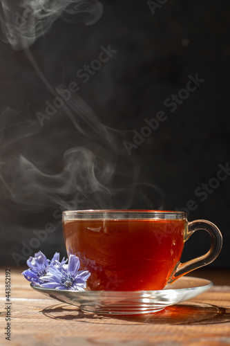 a glass mug with a chicory drink. A blue chicory flower floats in a cup with a drink