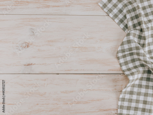 Kitchen napkin on a wooden table.
A checkered kitchen napkin lies on the right on a wooden table with space for text on the left, flat lay close-up.