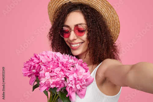 Positive young woman taking selfie with flowers