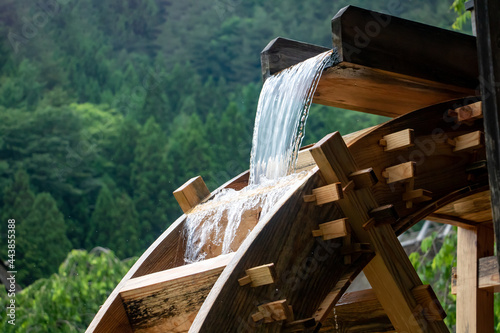 The mill wheel rotates under a stream of water, close up.