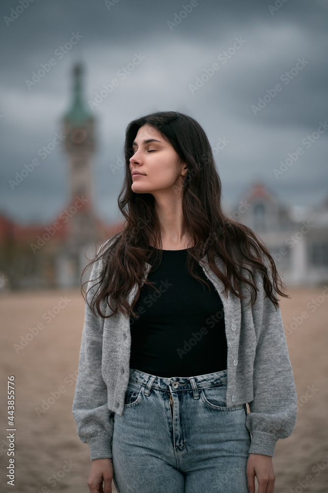 Sensual and gorgeous brunette on the beach. Clothed woman on the beach during autumn season on the seaside. Portrait of girl with brown hair wearing black shirt and jeans. Sensual and gorgeous brunette on the beach. Clothed woman on the beach during autumn season on the seaside. Portrait of girl with brown hair wearing black shirt and jeans.