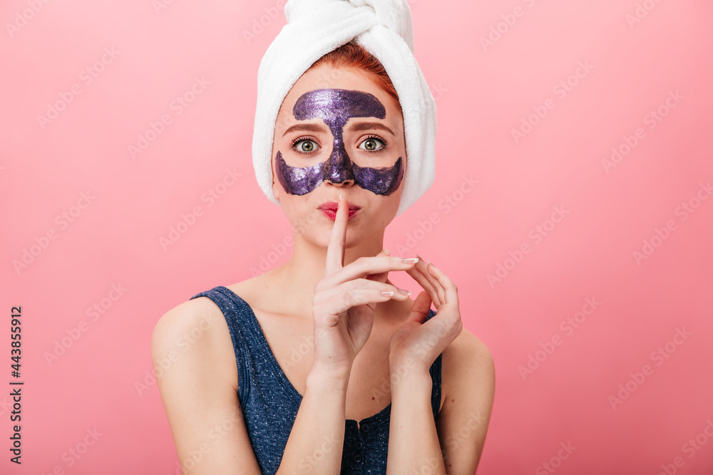 Front view of woman with face mask showing hush sign. Studio shot of young lady in posing on pink background during skincare treatment. Stock Photo | Adobe Stock