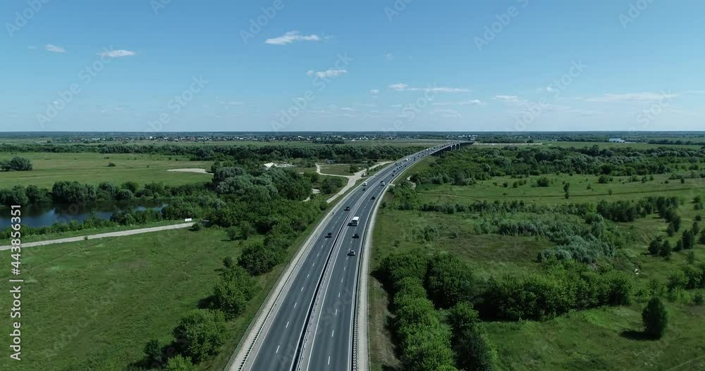 Aerial view of the movement of cars on the road near the lake to the bridge over the river on a summer sunny day Aerial view of the movement of cars on the road near the lake to the bridge over the river on a summer sunny day