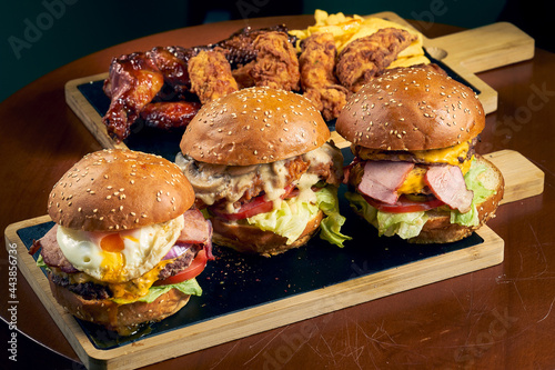 Three beef burgers with cheese  egg and salad on a black board. Fast food