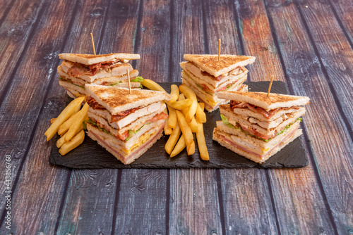 Great club sandwiches with lots of bacon-filled flats, fried eggs, lettuce, cheese, ketchup, ham, chicken fillets and a side of French fries.