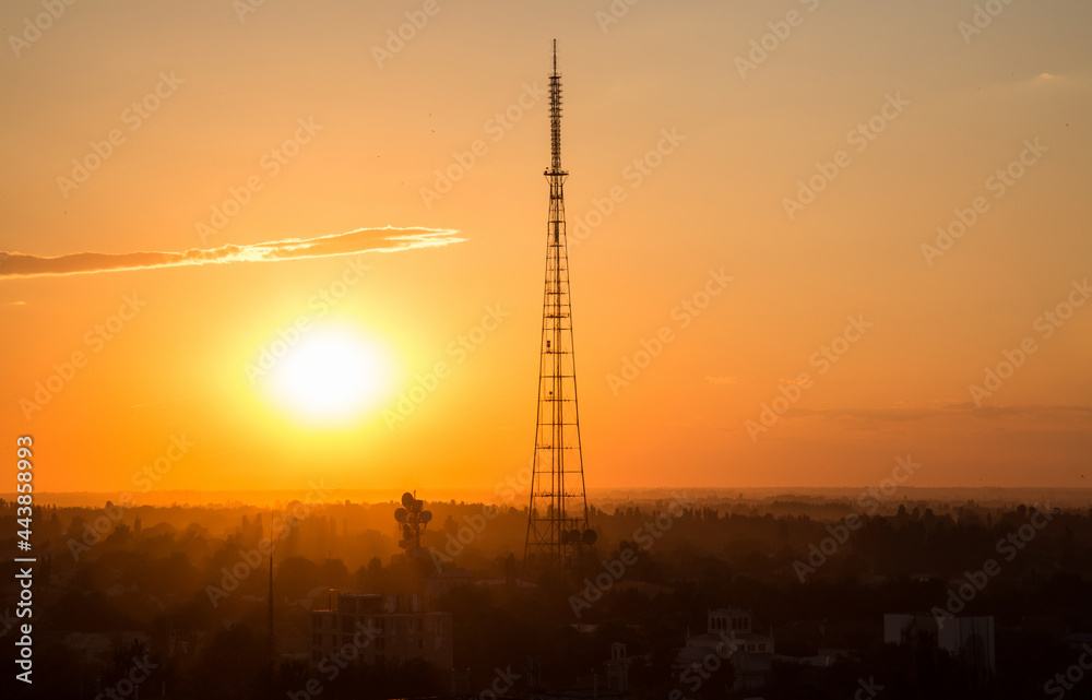 Fototapeta premium Stunning sunset in the city with the silhouette of a radio tower