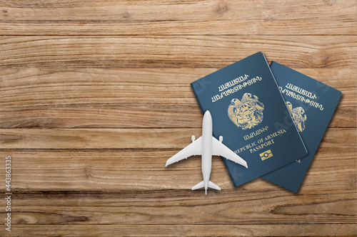 two Armenian  passport and airplane model on a wooden board  photo