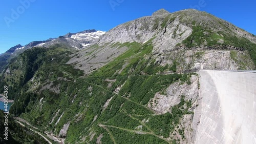 A panoramic view on the valley from the Koelnbrein Dam in Carinthia, Austria. The dam is surrounded by high Alpine peaks. Steep slopes. There is a long lake at the bottom of the valley. Natural energy photo