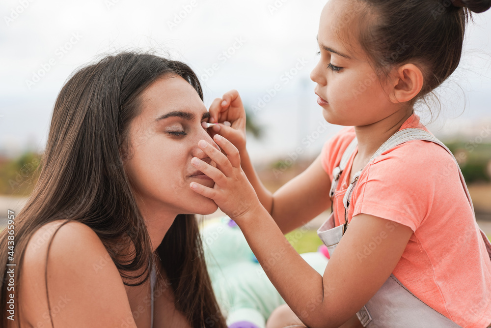 Cute little girl using children make up with big sister outdoor at city park - Family love concept Cute little girl using children make up with big sister outdoor at city park - Family love concept