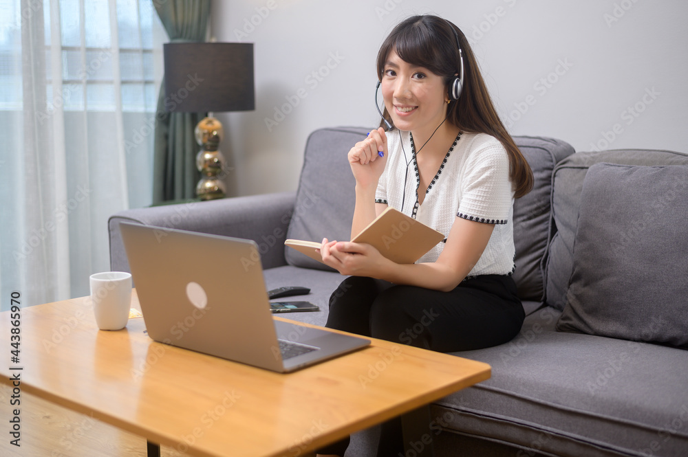 Beautiful young woman wearing headset is making video conference call via computer at home Beautiful young woman wearing headset is making video conference call via computer at home
