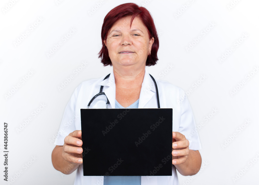 Mature female doctor holding a chalkboard in the studio.
Mature female doctor holding a chalkboard in the studio.