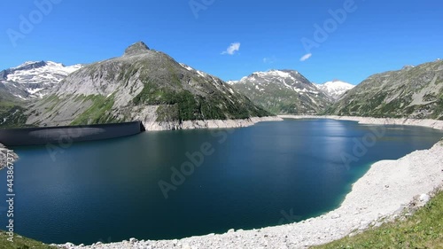 Panoramic view on the artificial lake at the Koelnbrein Dam in Carinthia, Austria. The dam is surrounded by high, snow-capped Alpine peaks. Steep slopes. The lake has a navy-blue color. Natural energy photo