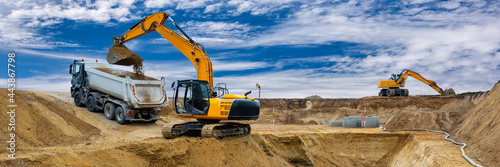 Fotografi excavator working on construction site with dramatic sky