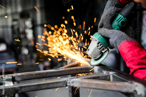 Welder used grinding stone on steel in factory with sparks, Welding process at the industrial workshop, hands with instrument in frame.