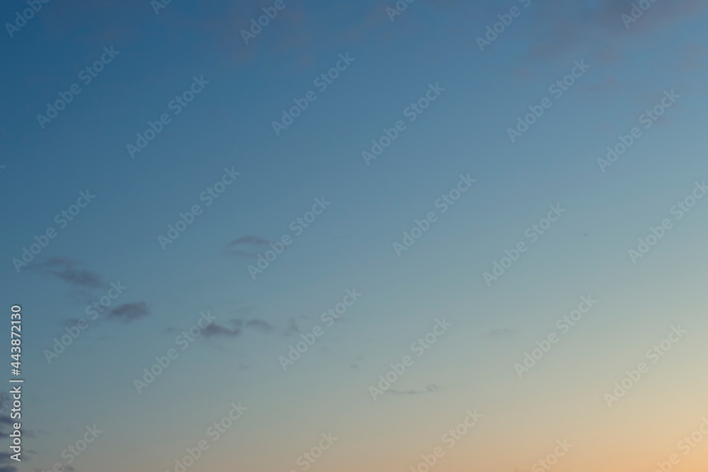Gradient sunset sky with a few small gray clouds. Nature background image
