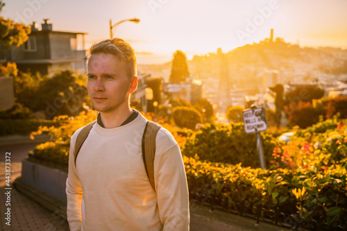 A young man stands on a beautiful Lombard Street during sunset in San Francisco