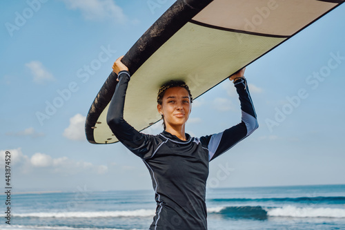 Photography Cheerful woman in wetsuit holding surfboard on beach