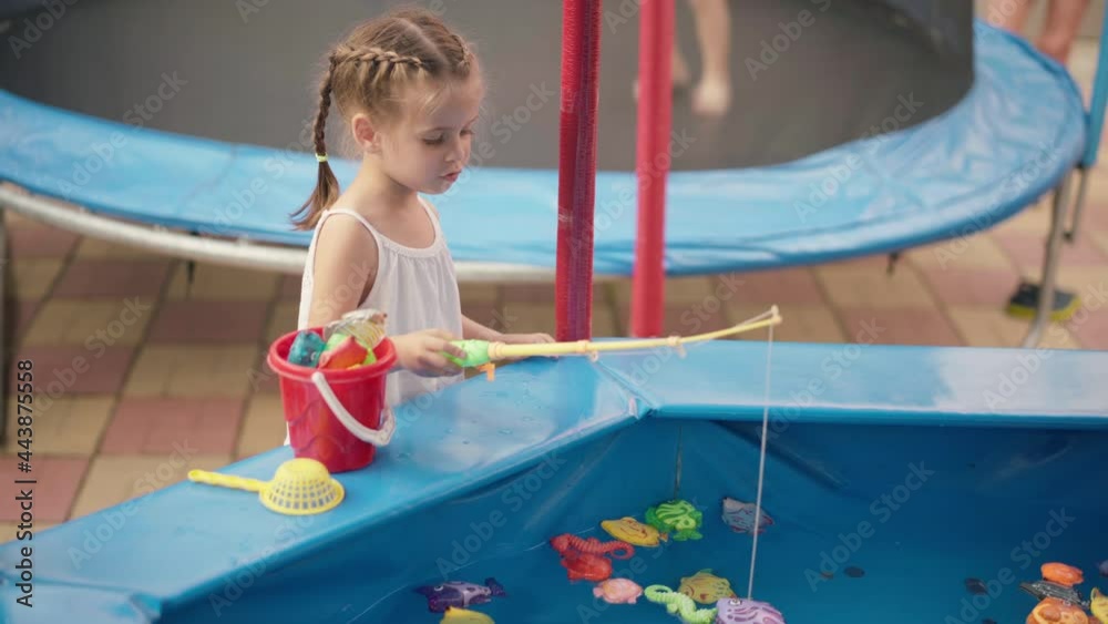Child Fisher Catching Plastic Toy Fish On Pool Amusement Park Summer Day Little Girl Have Fun On Fishing Carnival Festival Entertainment For Children