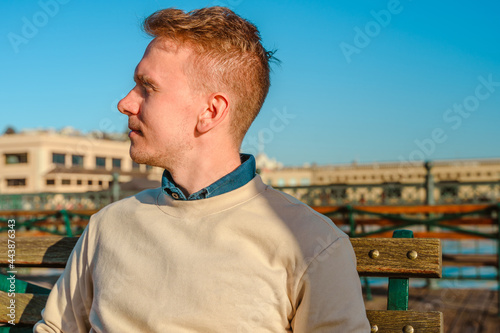 An attractive young man walks along the pier with a view of downtown in the morning in San Francisco