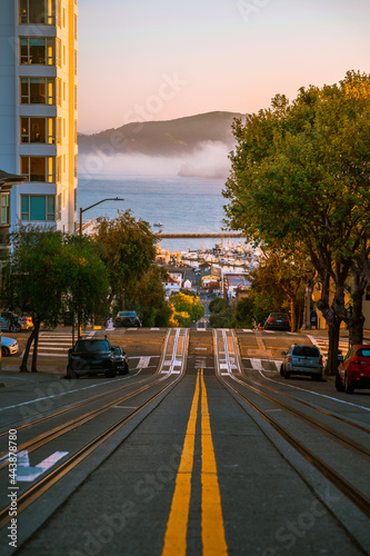 Photography Amazing view of a sloping street in San Francisco, photographed in the middle on the tram tracks