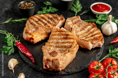 grilled pork steaks with spices on a stone background